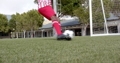 African American Soccer Player Kicking Ball Toward Goal on Field