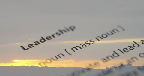Leadership double exposure overlaying dictionary entry with sunset horizon silhouette