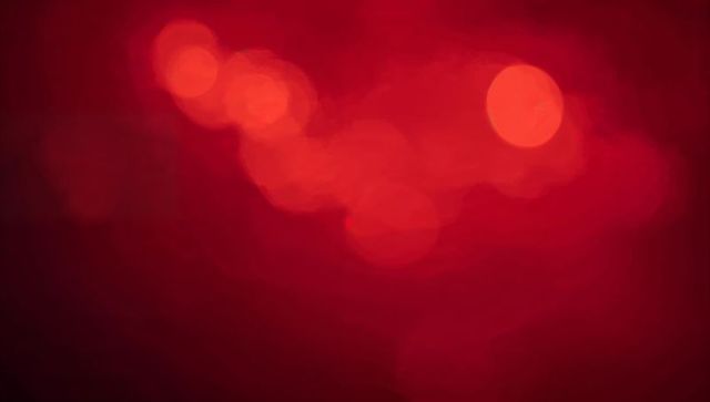 Crimson bokeh lights abstract background with soft glowing red orbs and gradient glow