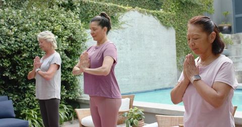 Women practicing morning meditation by backyard pool in activewear for wellness lifestyle