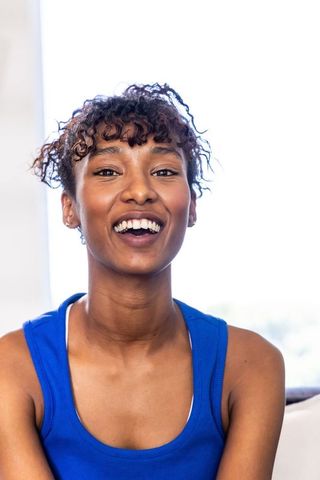 Radiant african american woman smiling in blue tank top, candid backlit headshot portrait