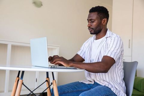 Focused Young Man Working on Laptop in Modern Home Office