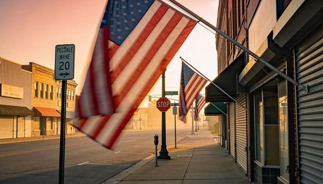 American flags fluttering along quiet small-town main street at golden sunrise