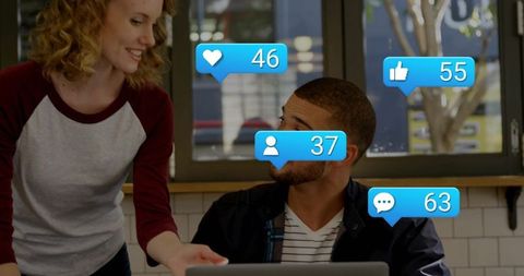 Smiling woman leaning toward man at cafe coworking table with social notifications