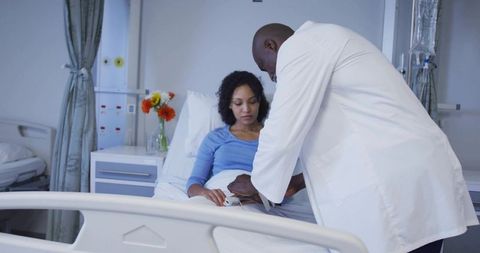Doctor examining patient wrist with pulse oximeter in hospital bed