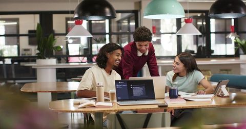 Young multiracial team collaborating around laptops in modern open-plan coworking space