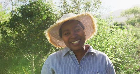 Smiling Senior Woman in Sun Hat Enjoying Outdoor Garden