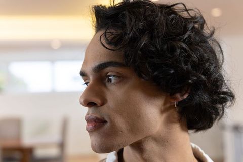 Young man looking away in warm office profile with curly hair and hoop earring