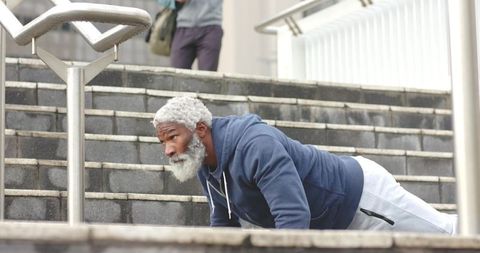 Mature African American Man Doing Push-Ups on Urban Staircase Wearing Hoodie for Workout