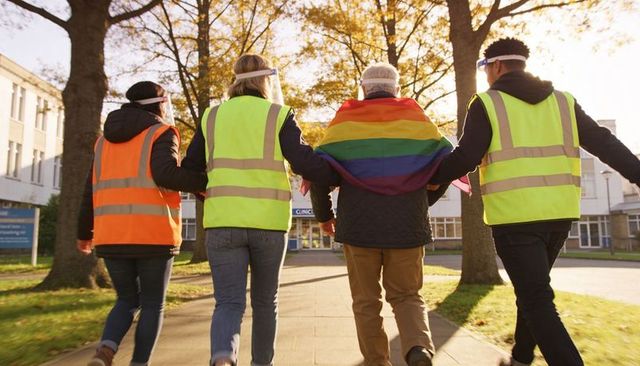 Campus volunteers walking toward clinic wearing rainbow pride flag and hi-vis vests