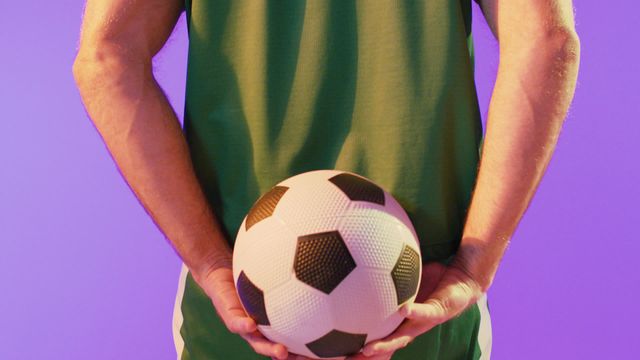 Image captures male soccer player in vibrant neon pink lighting. Ideal for promoting sports events, advertising athletic gear, and illustrating blog posts about soccer techniques or training.