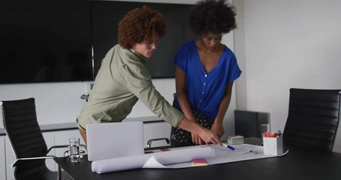 Two Professionals Collaborating on Architectural Plan in Modern Office