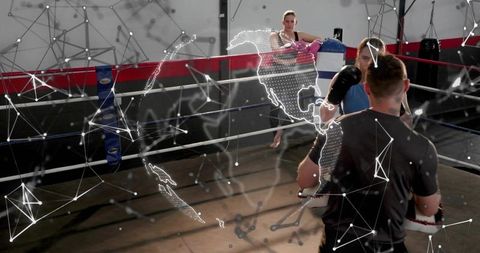 Boxing coach holding focus mitts in ring with boxer sparring and augmented reality globe