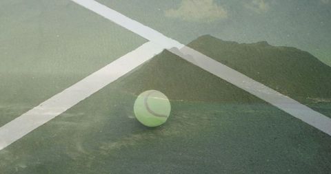 Tennis ball on court with scenic mountain reflection