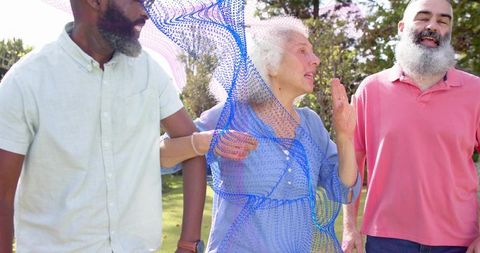 Seniors walking and linking arms in sunlit park with blue dotted mesh tech overlay