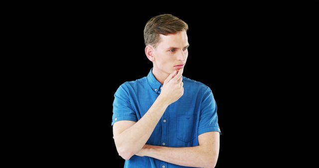 Young man in blue shirt deeply thinking with hand on chin against black background. Perfect for concepts of contemplation, decision-making, business, reflection, problem-solving, or advertising thinking services.