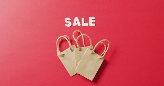 Sale text in white with three gift bags on red background with copy space. Luxury treat, present, shopping, sale and retail concept digitally generated image.