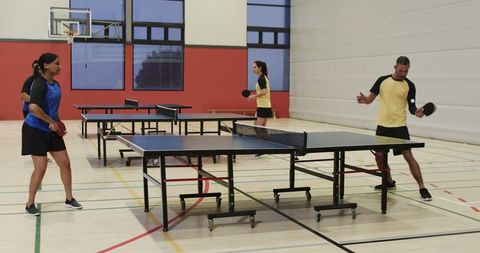 Adults engaging in competitive table tennis match indoors