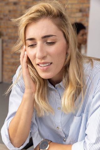 Mid adult woman focusing in modern office with brick wall background