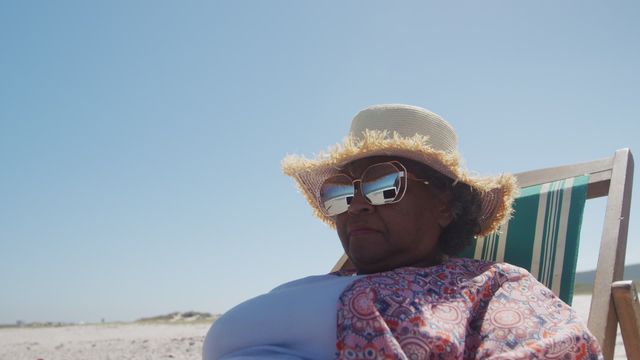 This video showcases a senior African American woman enjoying a sunny day at the beach. Perfect for publications on leisure and relaxation, retirement lifestyle, beach holidays, and senior tourism promotions.