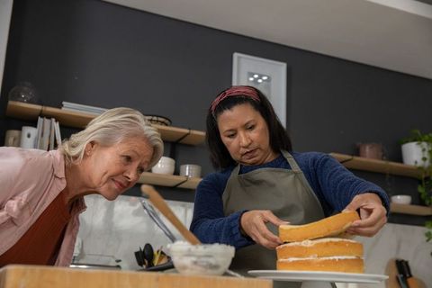 Assembling three-layer sponge cake together by diverse friends in modern home kitchen