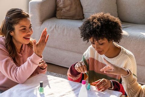 Sunlit at-home manicure party with diverse friends painting nails and laughing together