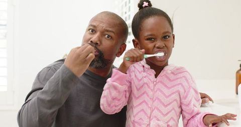 Father and daughter practicing oral hygiene together