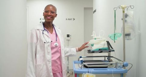 African female clinician in pink scrubs operating ventilator in radiology corridor