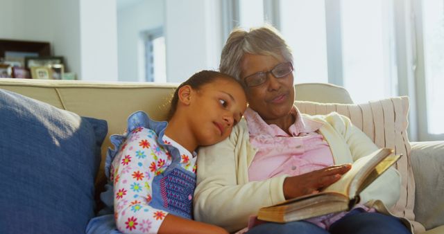 Grandmother Reading Book with Granddaughter on Couch - Download Free Stock Images Pikwizard.com