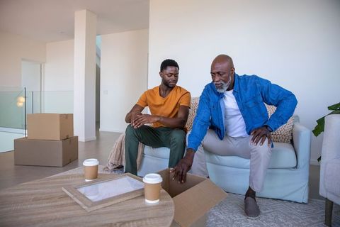 Father and Son Unpacking in New Living Room with Cardboard Boxes