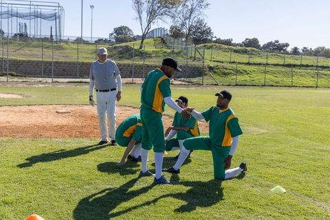 Baseball team warming up and shaking hands during outdoor practice on sunny field