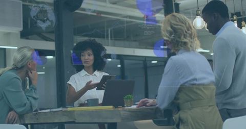Curly-haired leader presenting tablet to team in modern industrial workspace