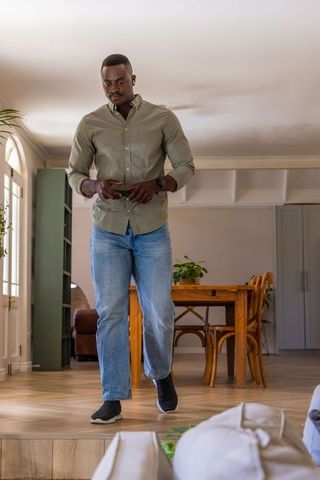 African american man checking smartphone while walking through modern minimalist interior