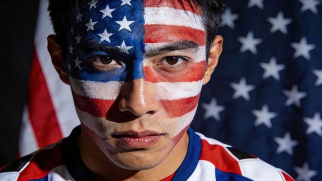Intense male portrait with full-face american flag paint and stars-and-stripes backdrop