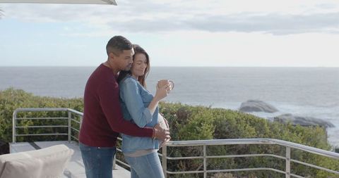 Expecting Couple Sharing Serene Moment by Ocean View