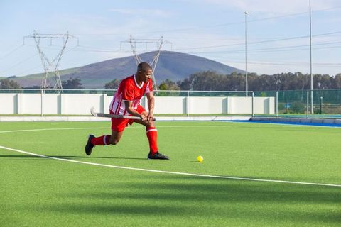 Dynamic athlete playing field hockey on outdoor turf