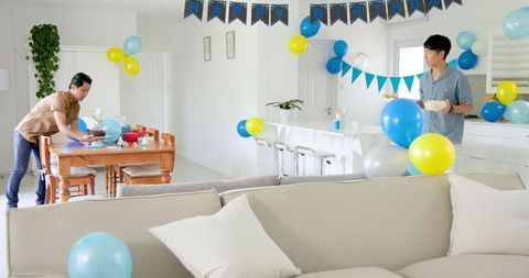 Men Preparing Colorful Balloon Decorations for Birthday Party at Home