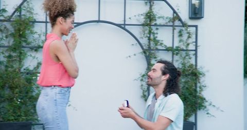 Man proposing romantic engagement to excited partner in garden setting