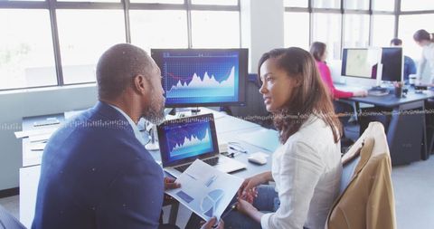Multiracial professionals discussing data in modern office environment