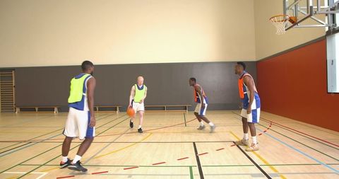 Diverse team of young men playing basketball indoors
