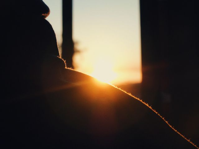 Silhouette of a man peacefully watching the sunset, with golden rays highlighting his shoulder. Excellent for themes related to relaxation, contemplation, mindfulness, natural beauty, tranquility, and endings. Suitable for website banners, blogs discussing peaceful concepts, and ads promoting mindful and serene lifestyle choices.