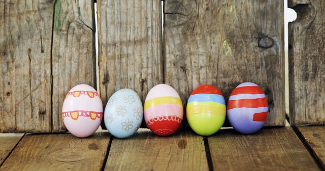 Colorful painted Easter eggs are lined up against a rustic wooden background, with copy space. These eggs symbolize the celebration of Easter and the tradition of egg decoration.