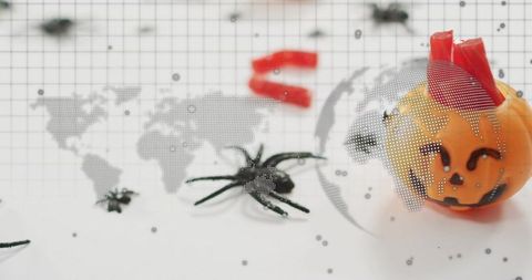 Halloween jack-o'-lantern candy with plastic spiders and dotted world map overlay