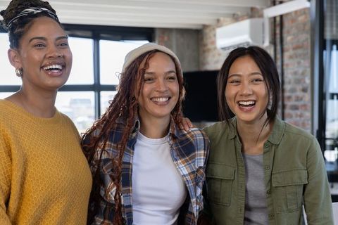 Happy Diverse Female Colleagues Enjoying Lively Conversation in Modern Office
