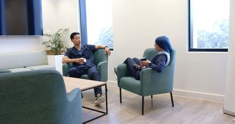 Multicultural healthcare team relaxing and chatting in bright staff lounge during break