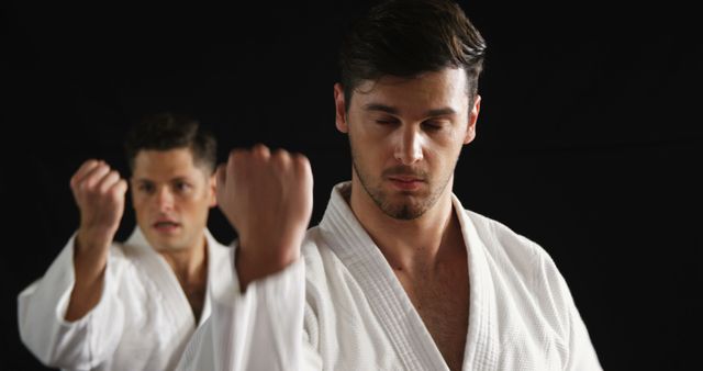 Men in white karate uniforms practicing punching technique with focused expressions, ideal for sports, martial arts promotion, training centers, self-discipline concepts, fitness, and self-defense campaigns.