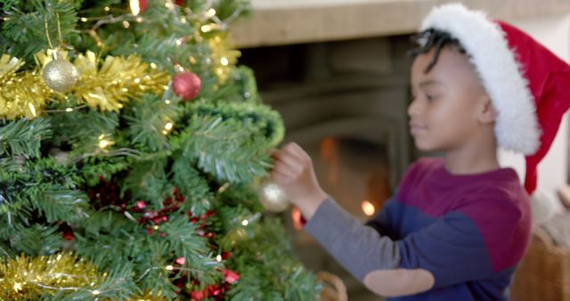 Child Decorating Christmas Tree with Santa Hat and Golden Ornaments - Download Free Stock Images Pikwizard.com