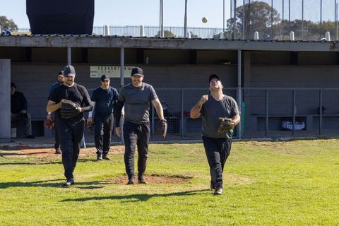 Sunlit amateur baseball team walking from dugout catching ball during practice