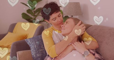Romantic Same-Sex Female Couple Embracing on Sofa with Styled Hearts