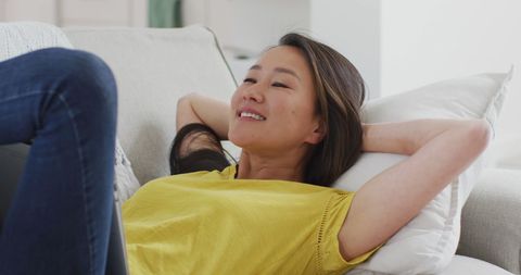 Smiling Young Woman Relaxing on Sofa with Laptop